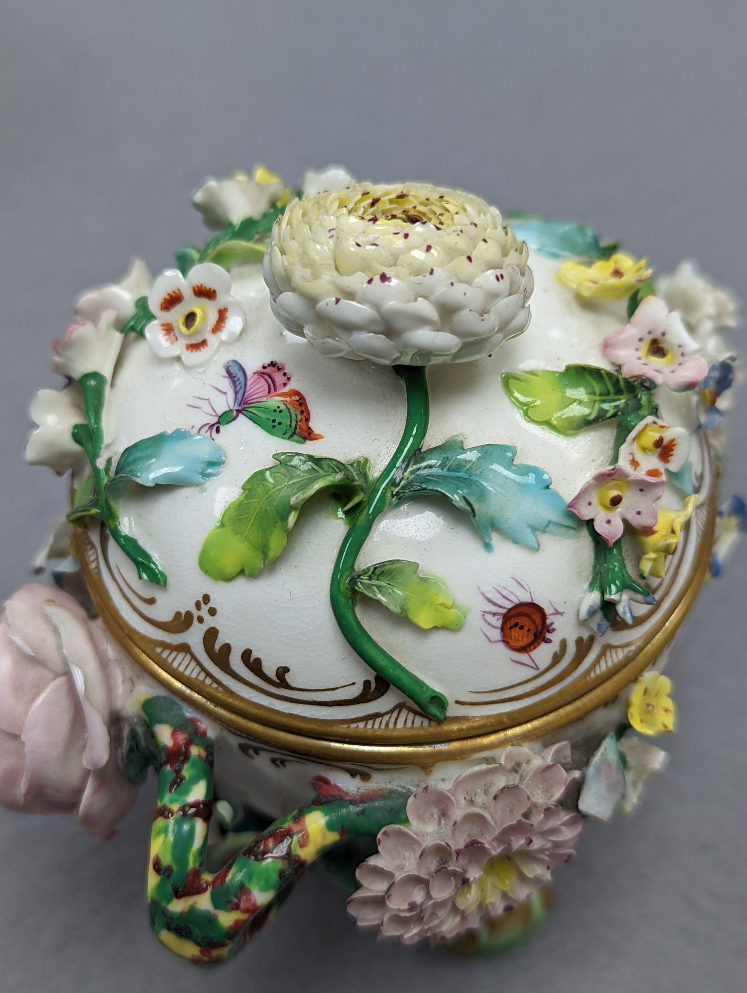 An 18th century Mennecy porcelain cup and cover, a Meissen style cup and cover, an English porcelain floral encrusted double inkwell and cover and a similar jar and cover